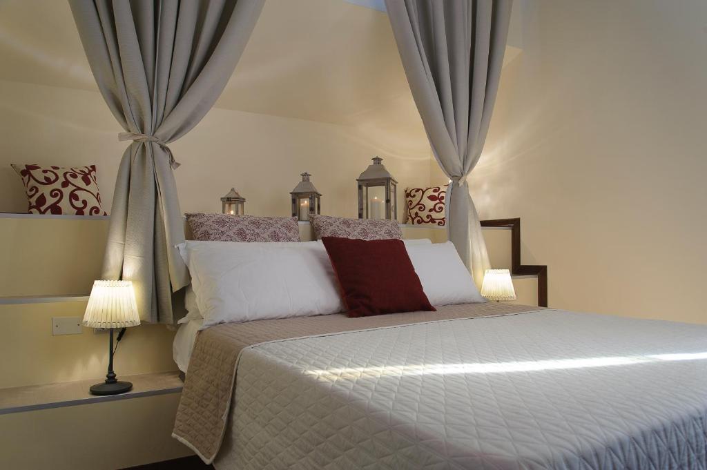 a bed with a white comforter and pillows at Xenía B&B in Piazza Armerina