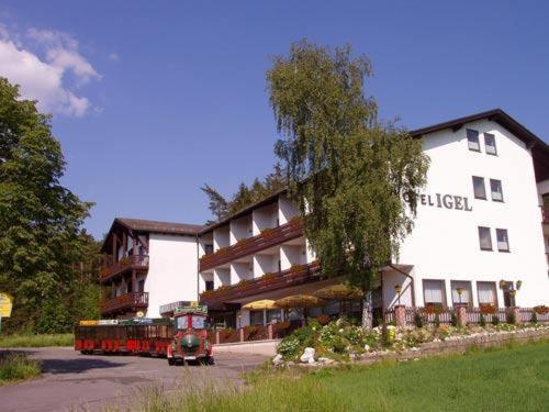 a bus driving past a hotel with a building at Hotel Igel in Püchersreuth