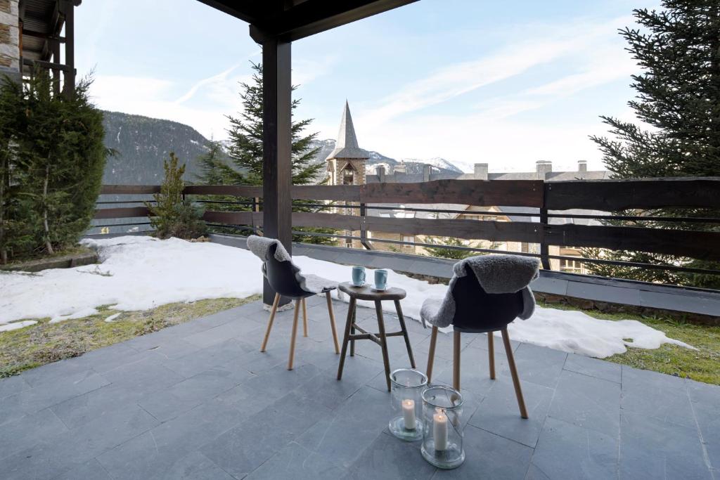 two chairs and a table on a patio with snow at Nin de Beret 4 by FeelFree Rentals in Naut Aran