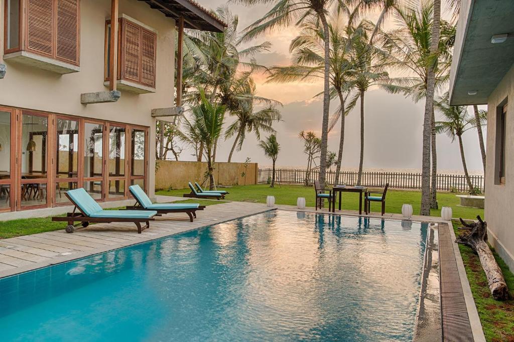 - une piscine avec des chaises bleues et des palmiers dans l'établissement Villa 700 by Amaya, à Bentota