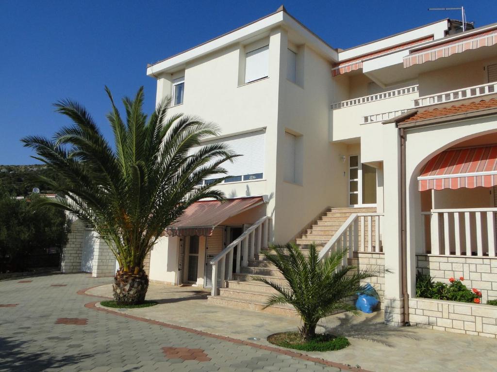 a white building with two palm trees in front of it at Zele in Dolac