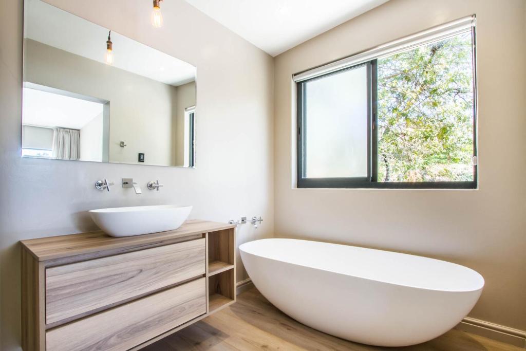 a bathroom with a large white tub and a sink at Hlangana Lodge in Oudtshoorn