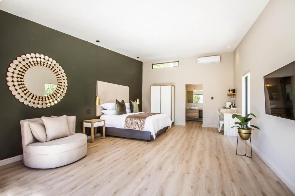 a large bedroom with a bed and a mirror at Hlangana Lodge in Oudtshoorn