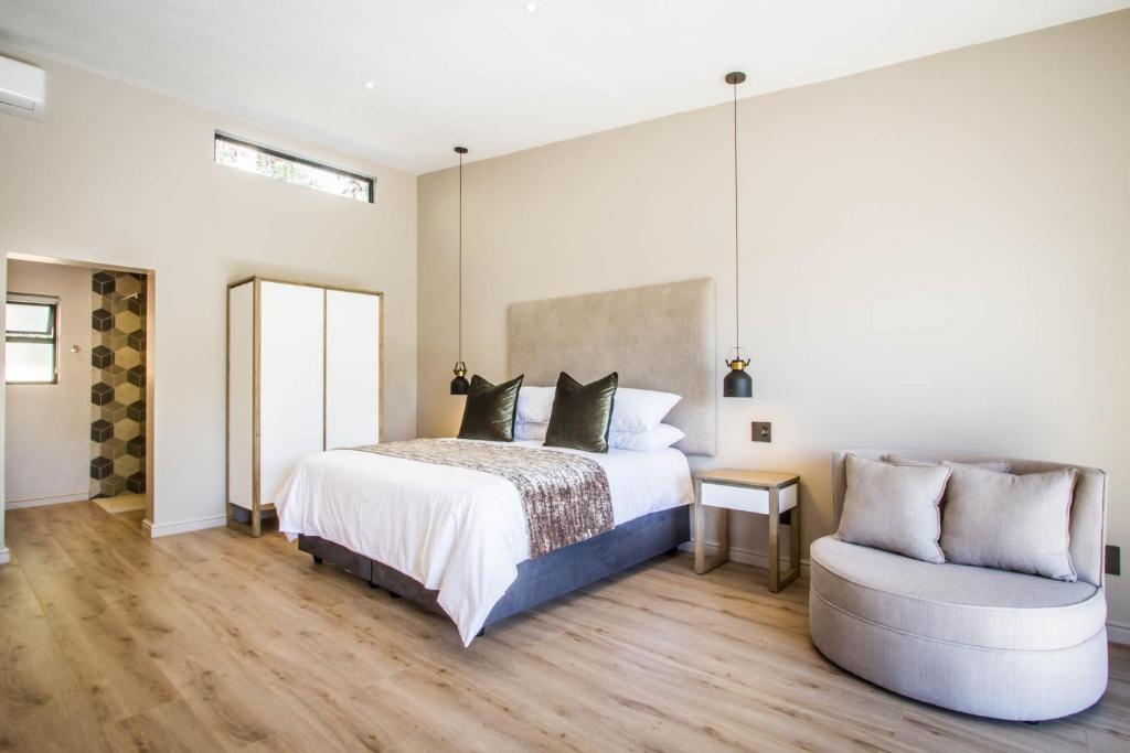 a bedroom with a bed and a chair at Hlangana Lodge in Oudtshoorn