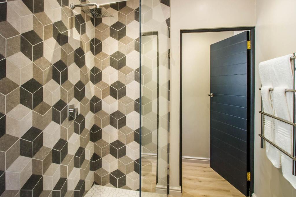 a bathroom with a shower with a tiled wall at Hlangana Lodge in Oudtshoorn