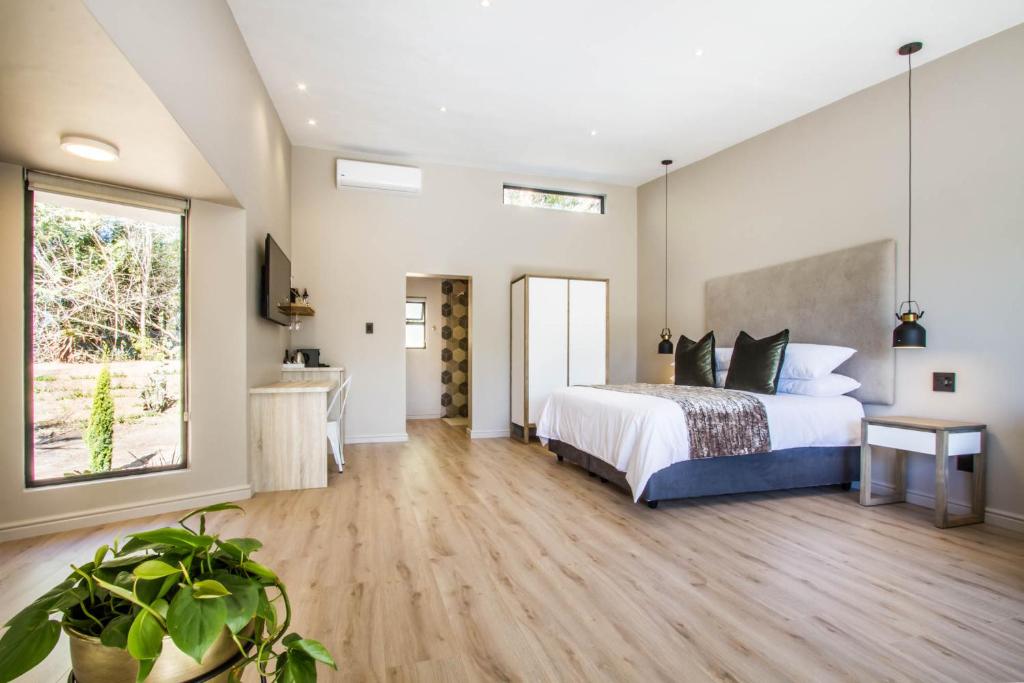 a bedroom with a bed and a large window at Hlangana Lodge in Oudtshoorn