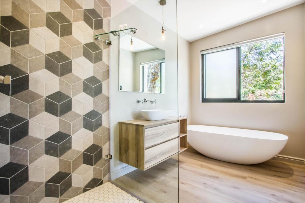 a bathroom with a tub and a sink and a mirror at Hlangana Lodge in Oudtshoorn