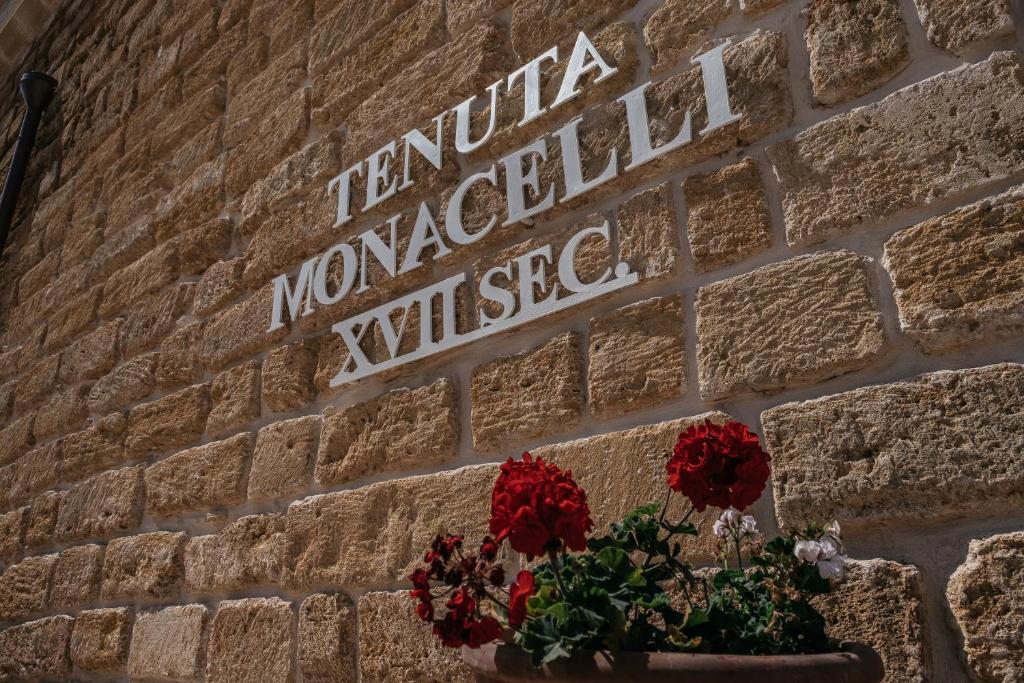 a sign on a brick wall with flowers in a pot at Tenuta Monacelli Lecce in Lecce