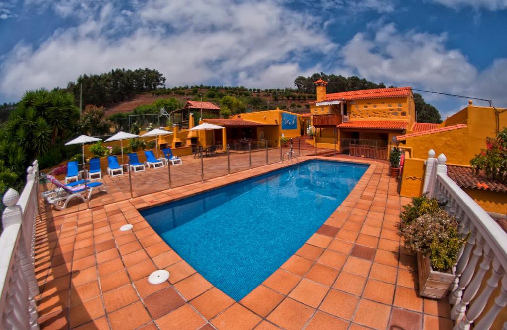 una piscina del complejo con sillas y sombrillas en Las Casas de Lola y Rafael, en Moya