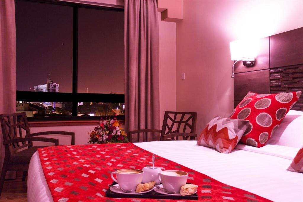 a hotel room with a bed with a tray of food on it at Bidwood Suite Hotel in Nairobi