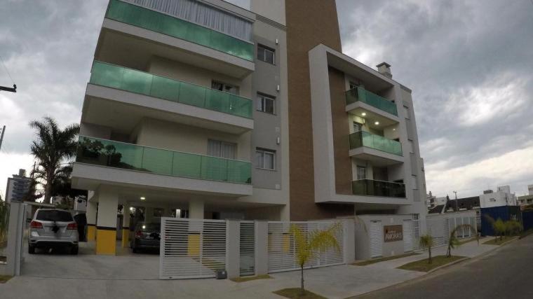 a large building with a fence in front of it at Ap Praia De Palmas in Governador Celso Ramos