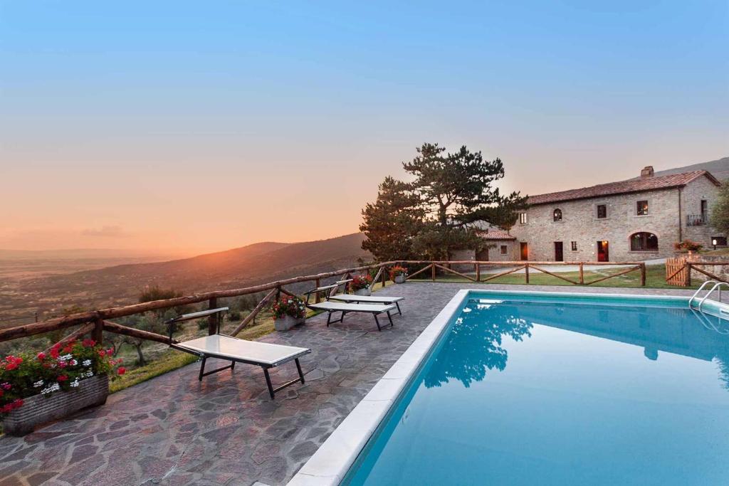a swimming pool with two tables and a building at Agriturismo Le Celle in Cortona