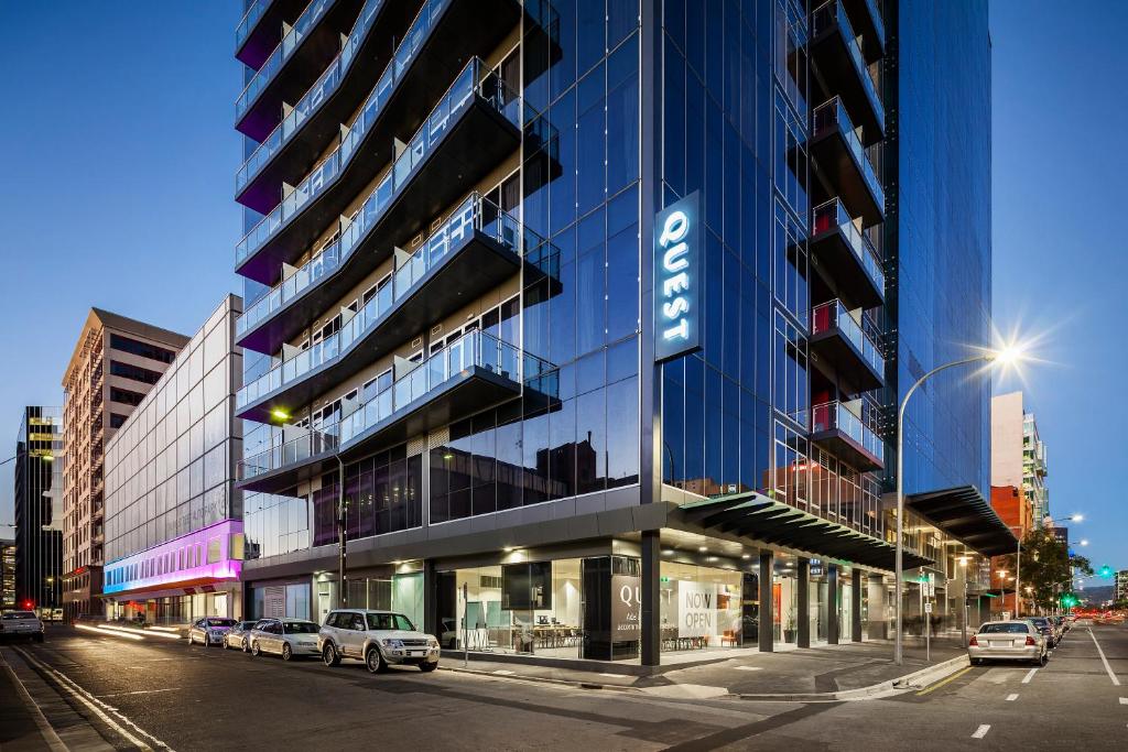 wysoki szklany budynek z samochodami zaparkowanymi przed nim w obiekcie Quest on Franklin w mieście Adelaide