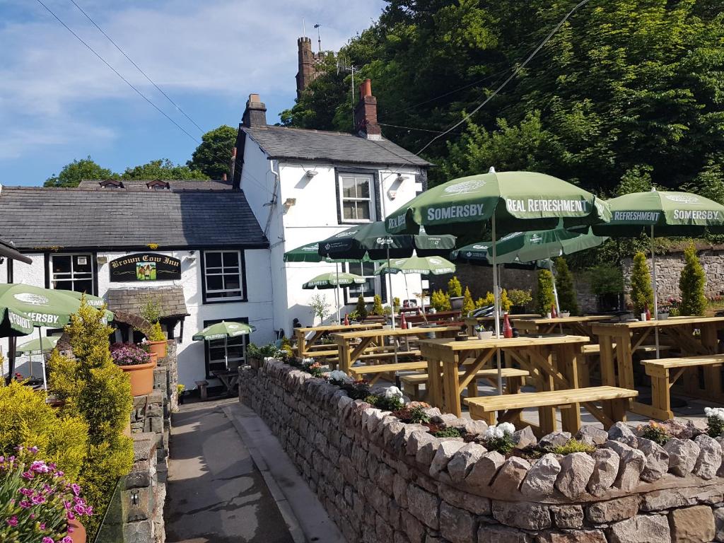 un restaurant avec des tables en bois et des parasols verts dans l'établissement Brown Cow Cottage, à Dalton in Furness