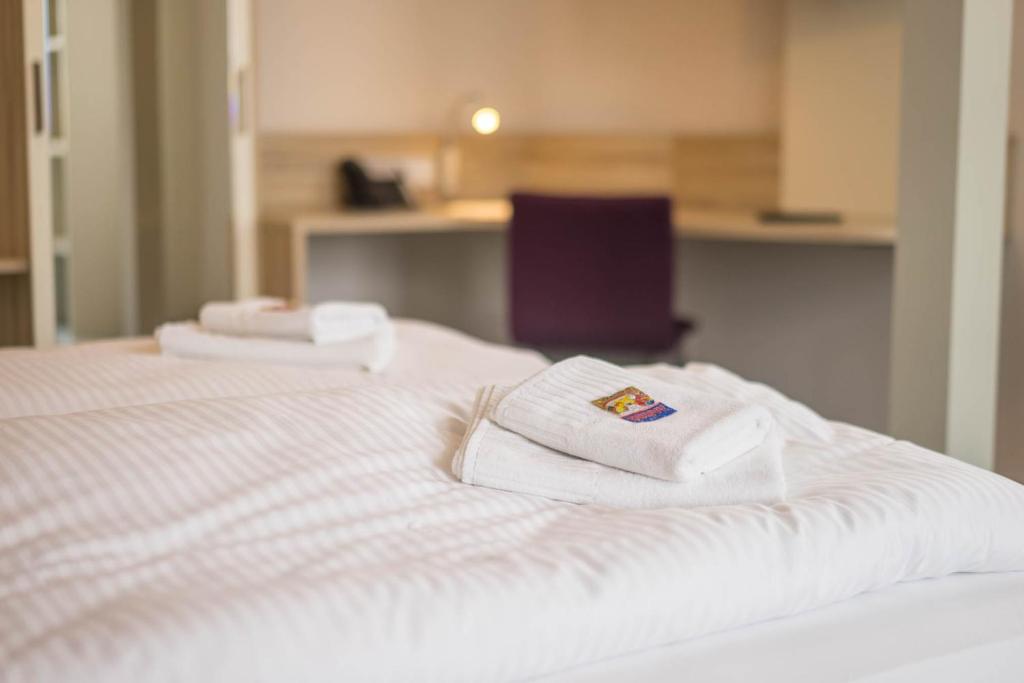 two white towels sitting on top of a bed at Schumanns Garten in Weißenfels