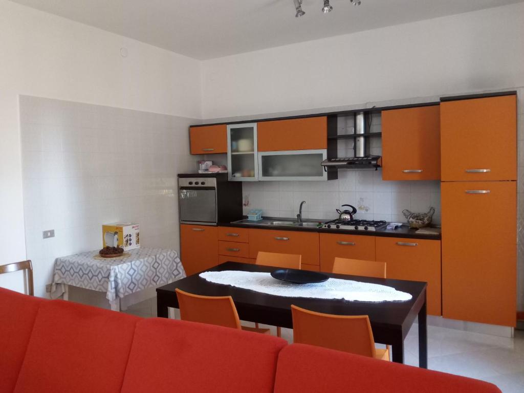 ブリンディジにあるCasa Paradisoのキッチン(オレンジ色のキャビネット、テーブル、椅子付)