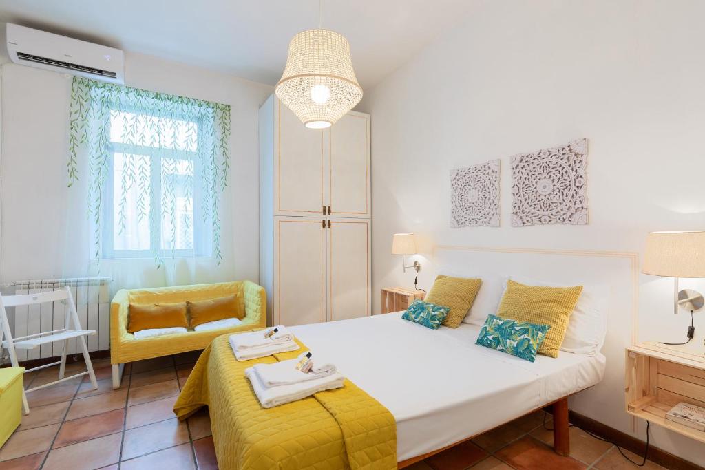 a bedroom with a white bed and a yellow chair at Rome As You Feel - Monti Apartment in Rome