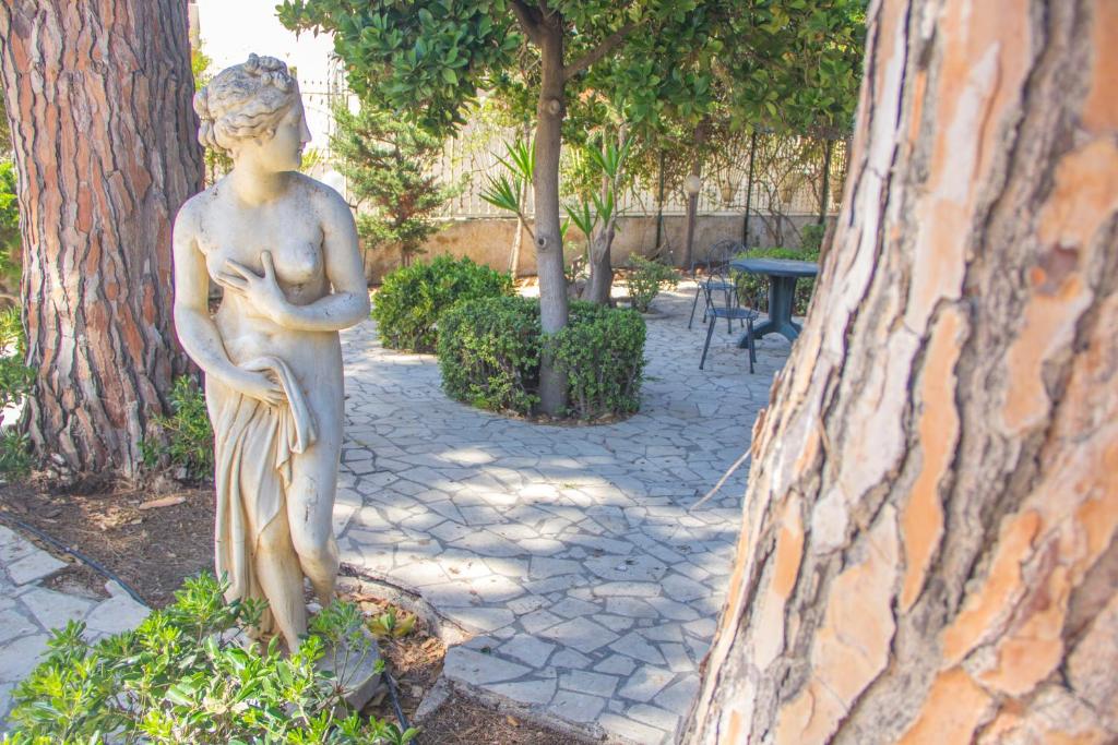 a statue of a woman standing next to a tree at Villa Speranza in Marausa