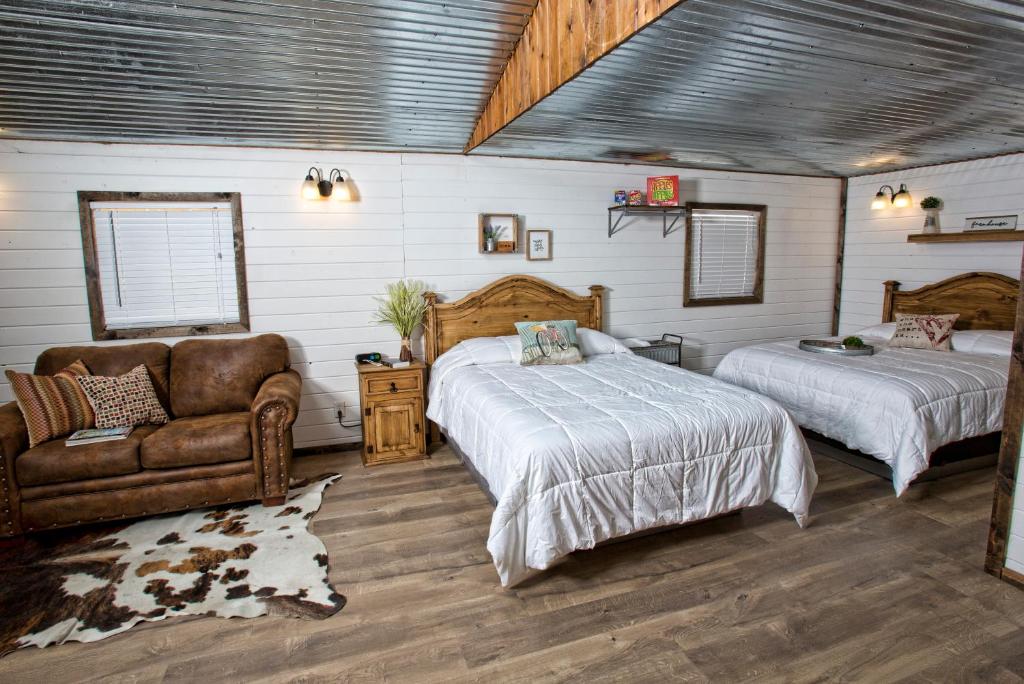 a bedroom with two beds and a couch and a chair at Stateline Cabin in Hobbs