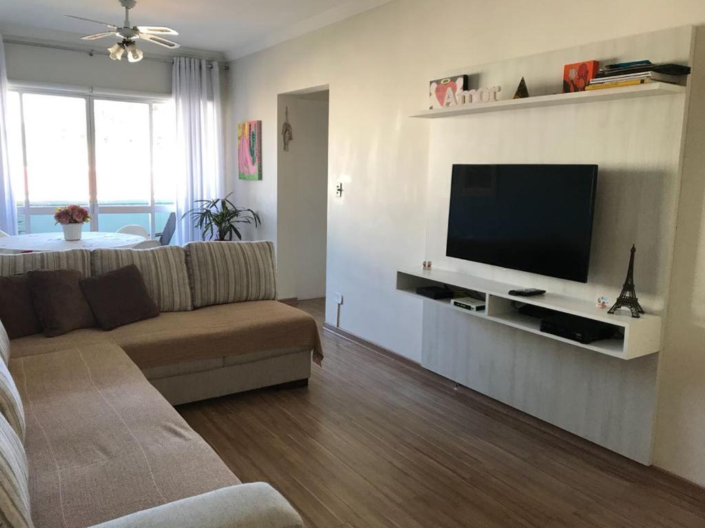 uma sala de estar com um sofá e uma televisão de ecrã plano em Apartamento Confortável Guarujá no Guarujá