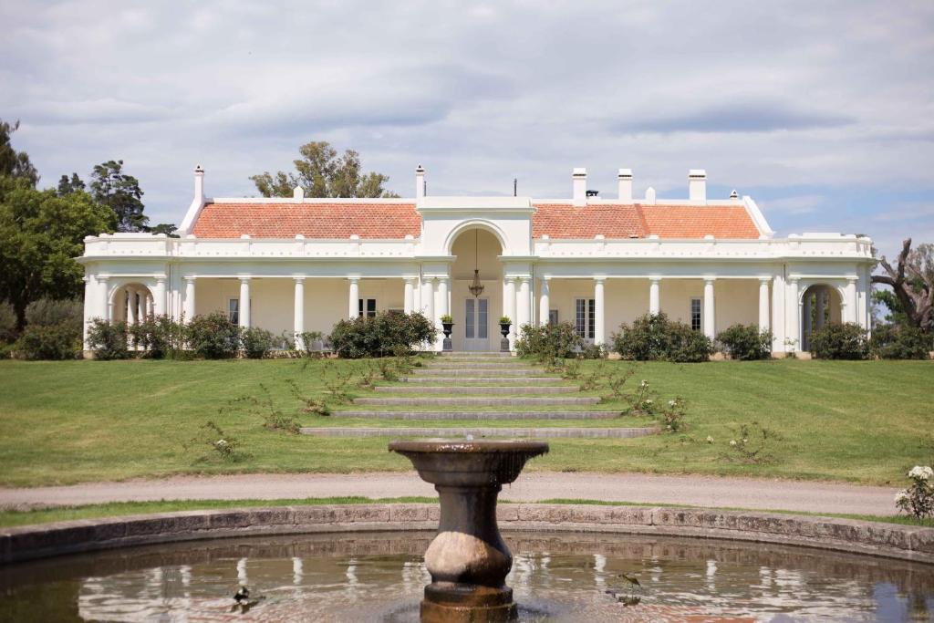 een groot wit huis met een fontein ervoor bij Estancia La Paz Hotel in Ascochinga