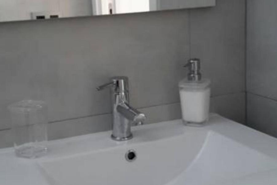 a bathroom sink with two faucets and a candle on it at Apartamentos en Paseo Maritimo in El Rompido