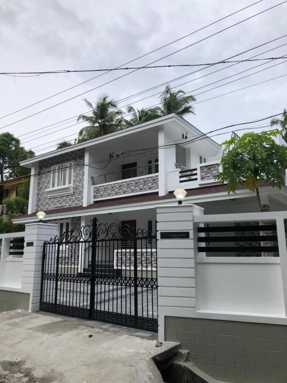 a white house with a black gate at Sannidhi Home stay in Guruvāyūr
