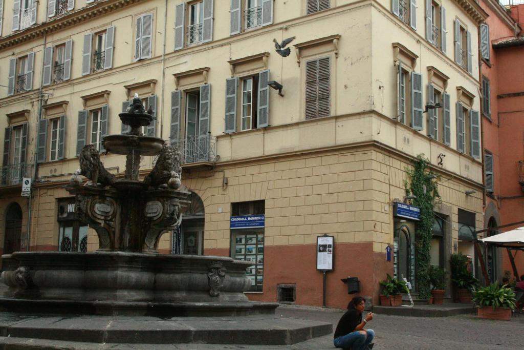 a woman sitting next to a fountain in front of a building at Antico Angelo - Residenza d'Epoca in Viterbo