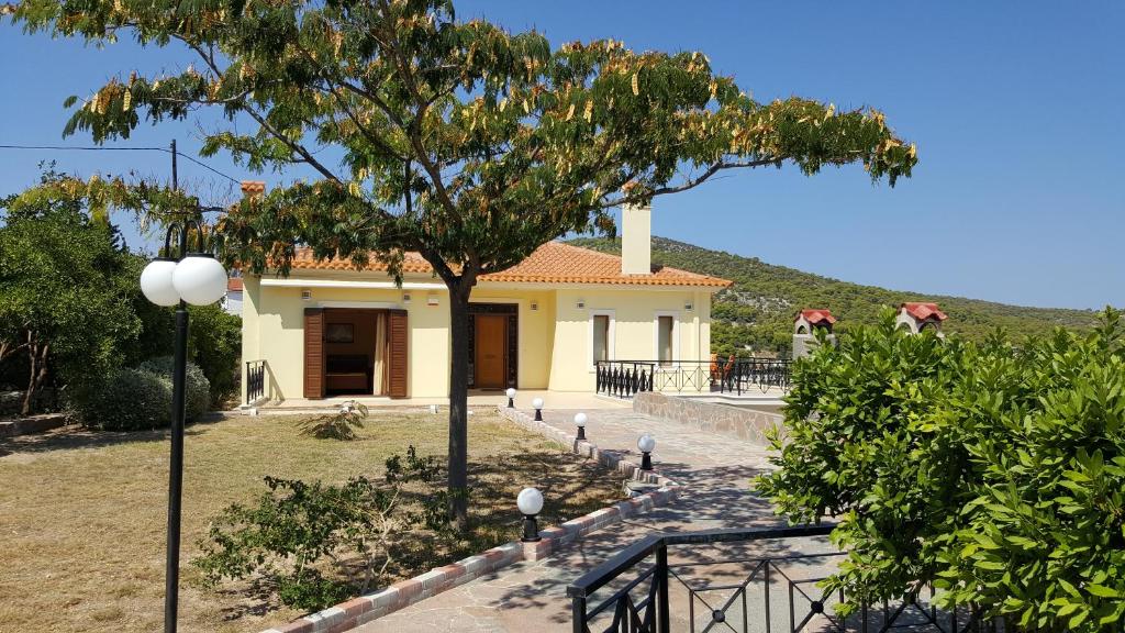 Villa Politimi at Aegina في Mesagrós: منزل أمامه شجرة
