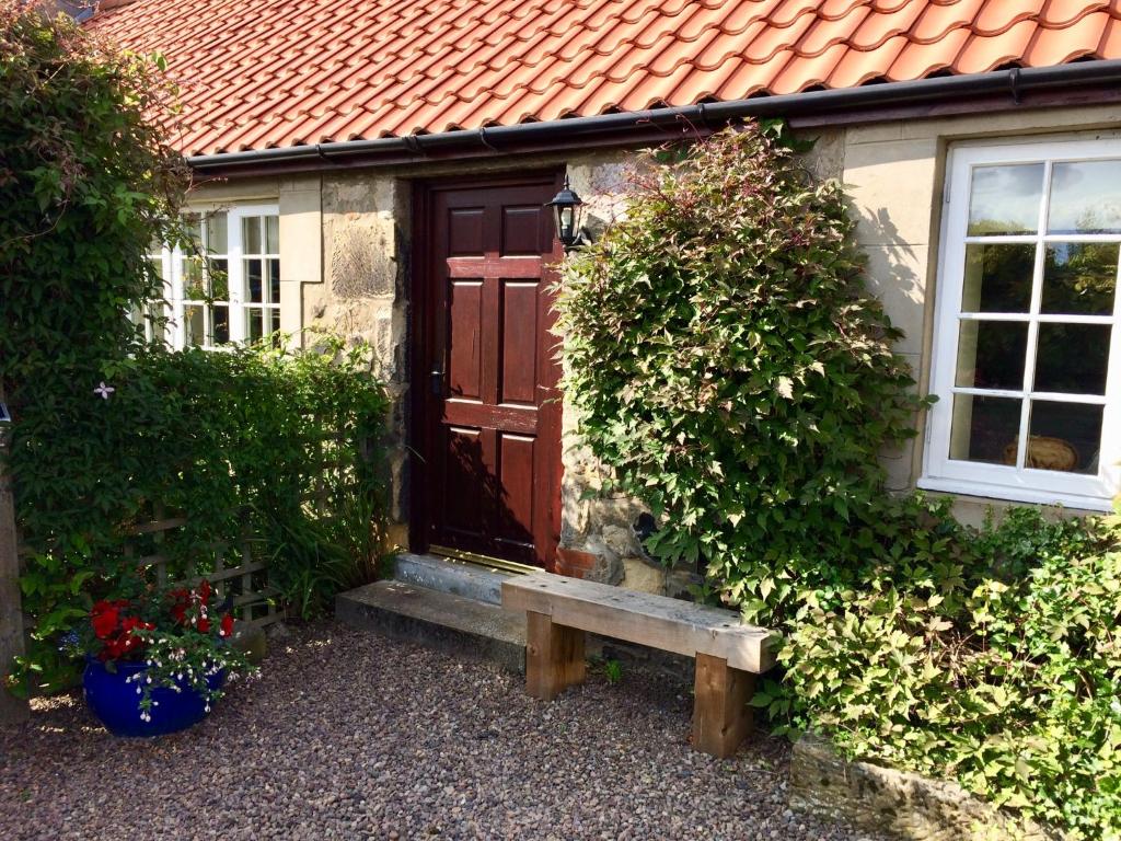 a house with a wooden door and a bench in front at The Cottage in Belford