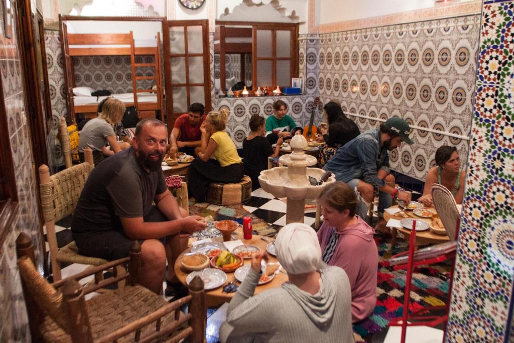 a group of people sitting around a table in a restaurant at Mosaic Hostel in Marrakesh