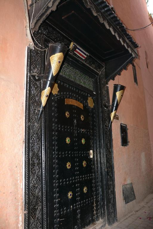 a large black door with two flags on top at Riad Assalam in Marrakech