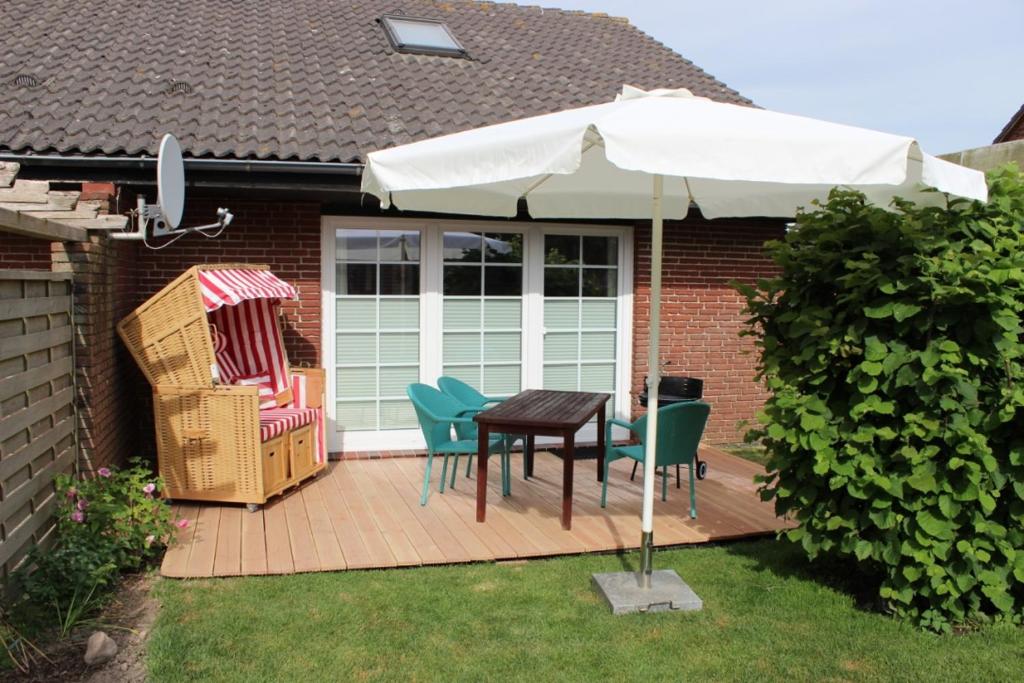 un patio con mesa, sillas y sombrilla en Ferienhaus Meerzeit, en Nordstrand