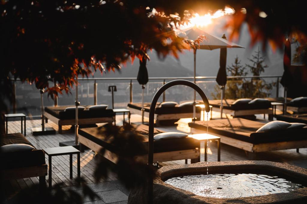 a group of beds in a courtyard with a hot tub at Miramonti Boutique Hotel in Avelengo