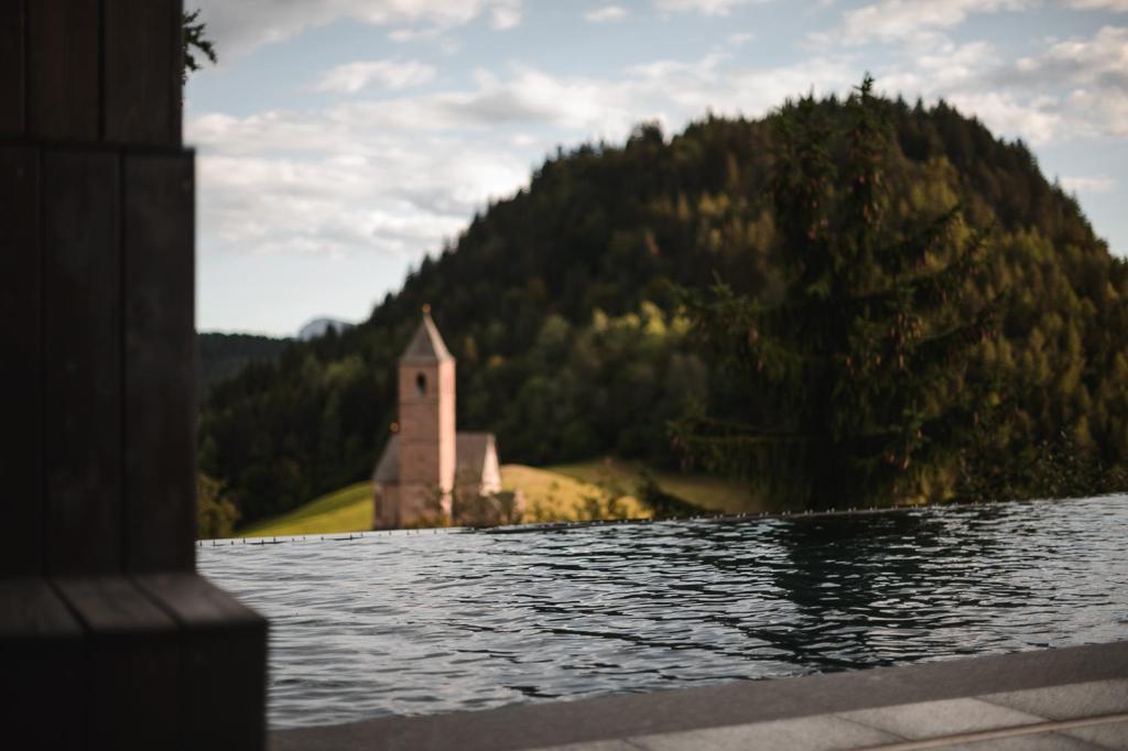 a church on the shore of a body of water at Miramonti Boutique Hotel in Avelengo