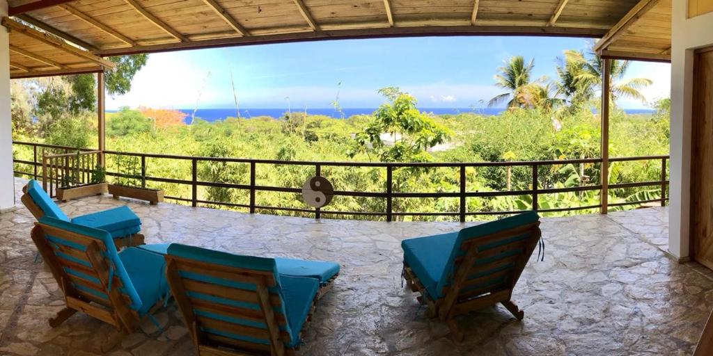 un patio con sillas azules y vistas al océano en B&B El Mirador al Mar en Sosúa