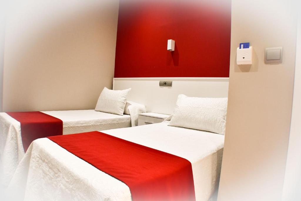 two beds in a room with red and white at Hostal Playa Candor in Rota