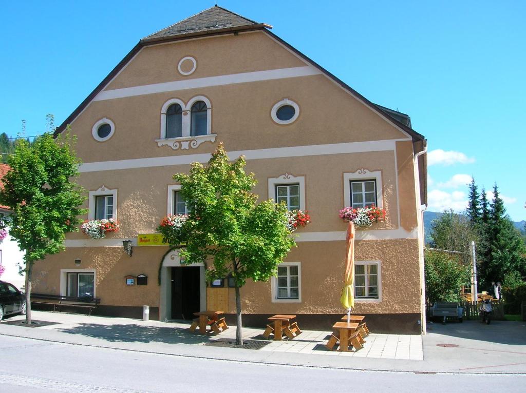 - un grand bâtiment avec des tables de pique-nique en face dans l'établissement Gasthof Murauerhof, à Sankt Peter am Kammersberg