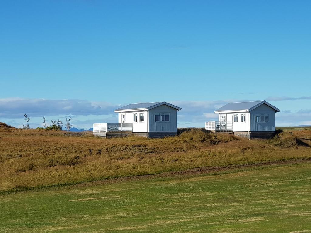 duas casas sentadas no topo de uma colina relvada em Beindalsholt em Hella