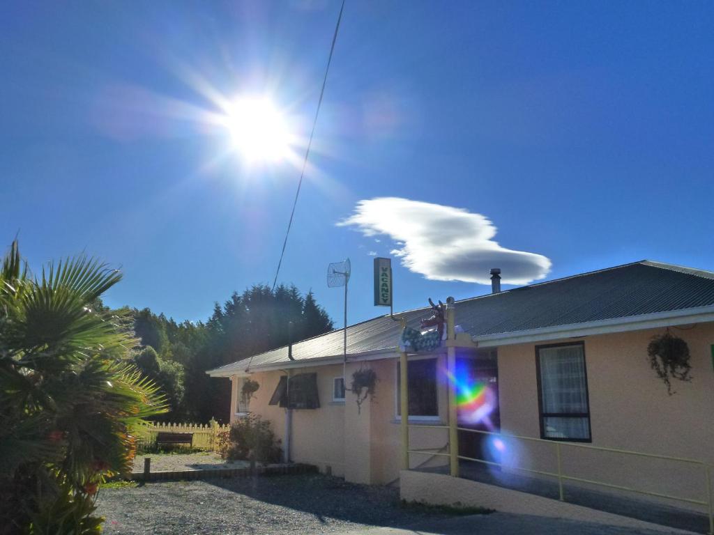 ein Haus mit der Sonne am Himmel in der Unterkunft The Lazy Cow Accommodation in Murchison