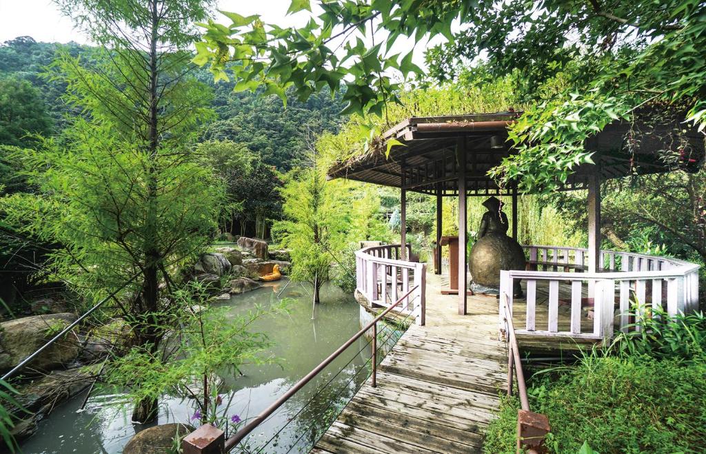 a bridge over a river with a statue on it at Tai-Yi Red Maple Resort in Puli