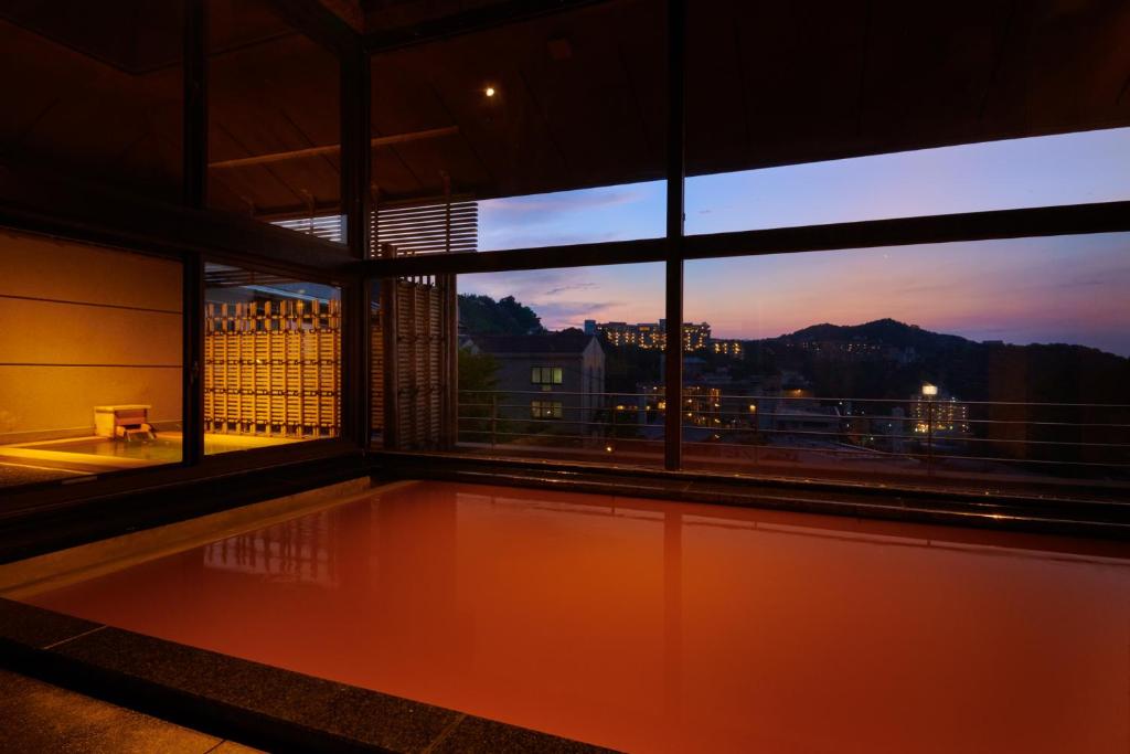 a room with a large window with a swimming pool at Arima Onsen Takayamaso Hanano in Kobe