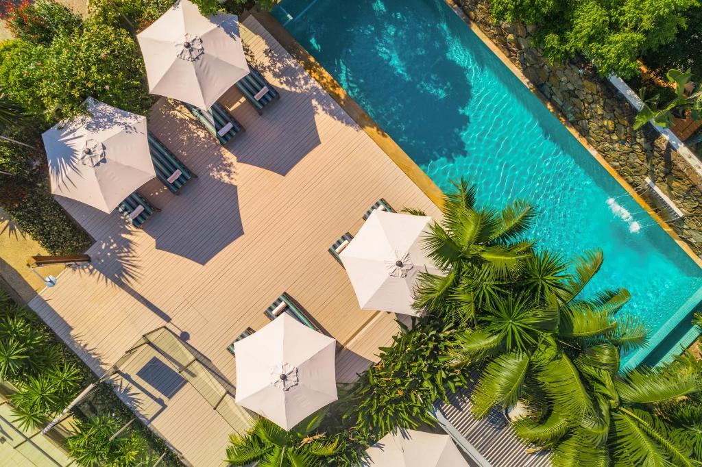 an overhead view of a beach with umbrellas and a swimming pool at Bayview Beachfront Apartments, in town right on the beach in Byron Bay