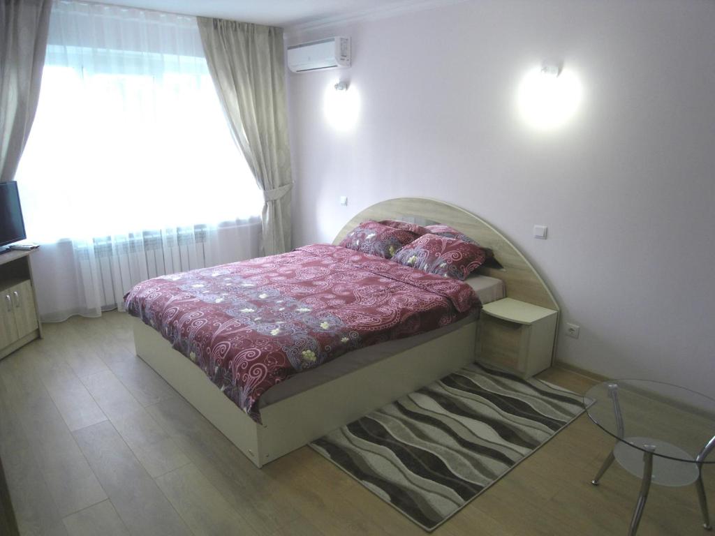 a bedroom with a bed and a table and a window at Modern Apartment in Chişinău