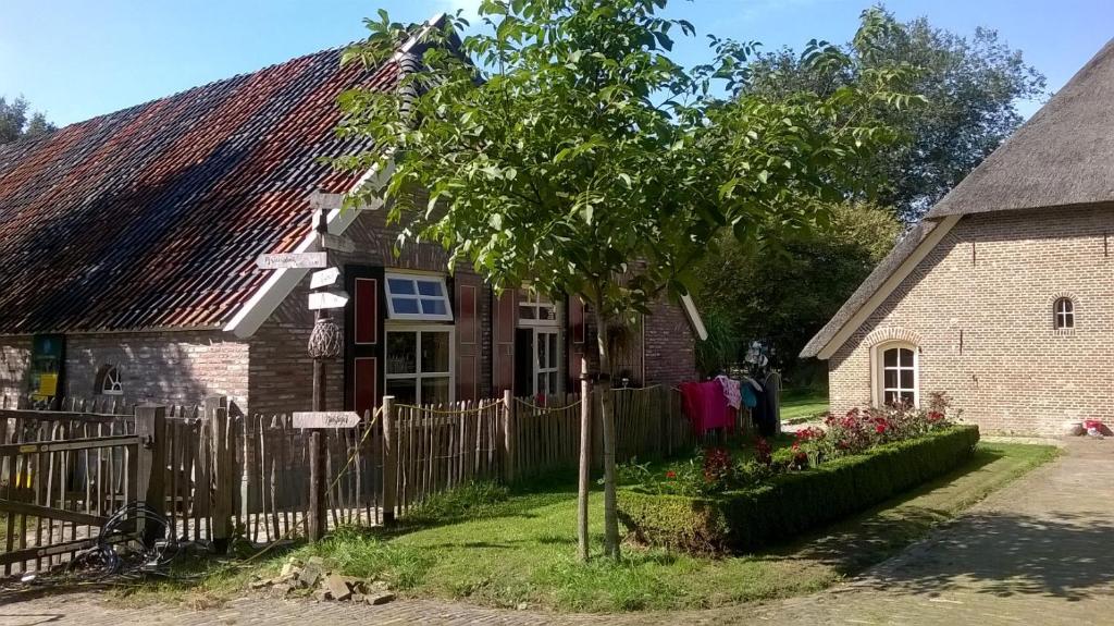 una casa vieja con una valla y un árbol en landgoed Groot Boerle, en Wijhe