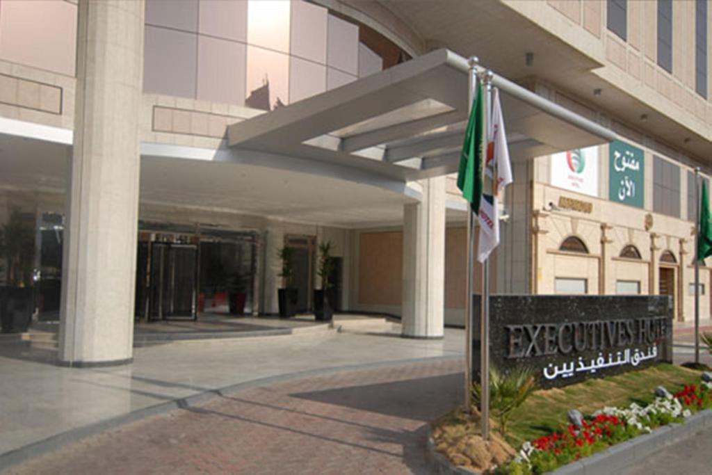 un edificio con una bandera y una señal delante de él en Executives Hotel - Olaya en Riad
