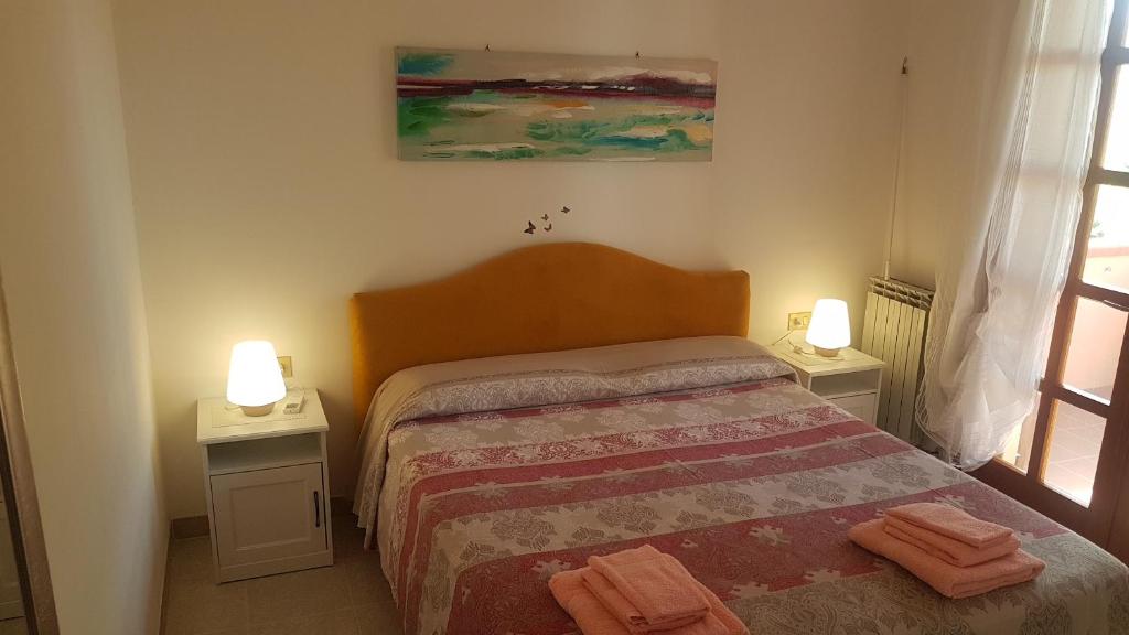 - une chambre avec un lit et deux lumières sur deux tables dans l'établissement La Vigna For Family, à La Maddalena