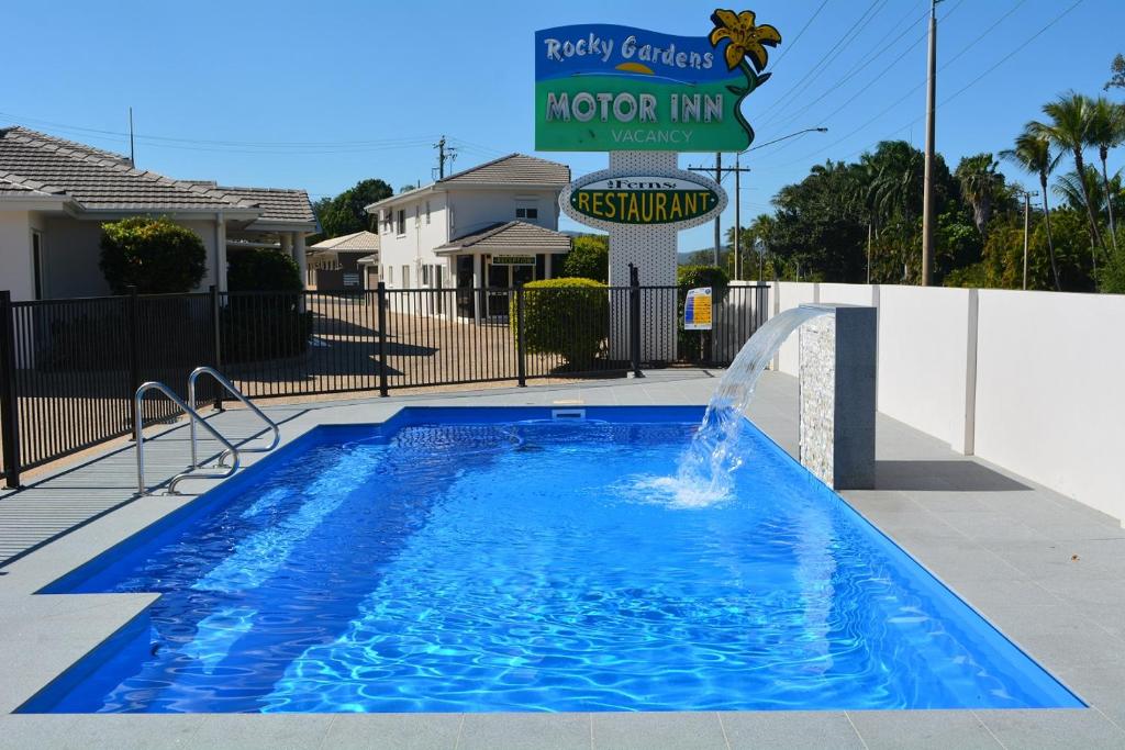 uma piscina com uma fonte de água em frente a uma placa em Rocky Gardens Motor Inn Rockhampton em Rockhampton