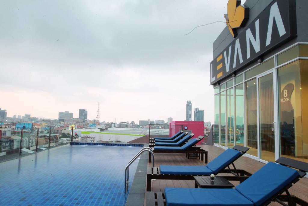 Levana Pattaya Hotel - SHA Extra Plus في باتايا سنترال: مسبح على سطح مبنى مع كراسي جلوس