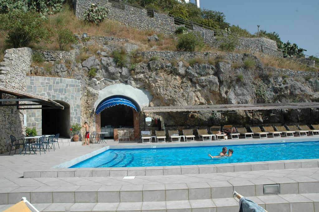 a person swimming in a swimming pool next to a mountain at Hotel Belvedere in Conca dei Marini